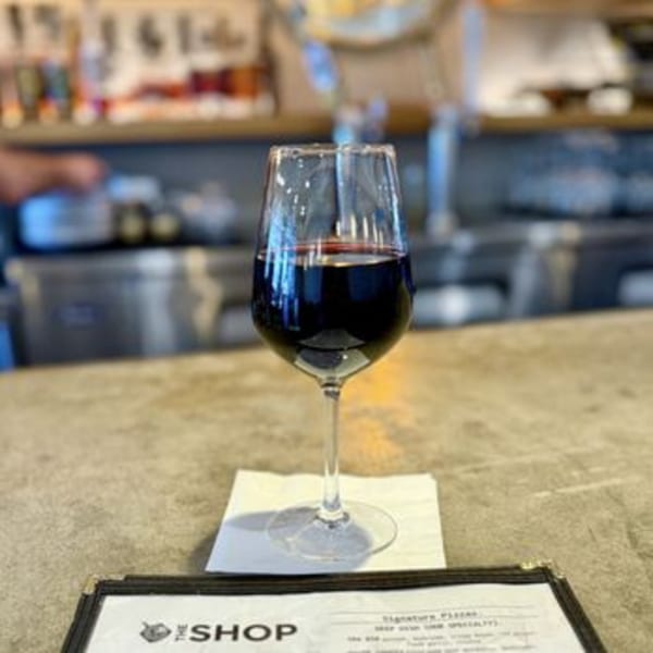 A glass of red wine sits on a menu at The Shop: Pizza + Cocktails.