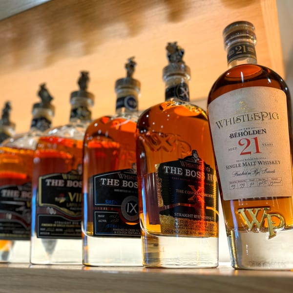 A close-up of several WhistlePig whiskey bottles, including "The Boss Hog" and "The Beholden 21 Years".