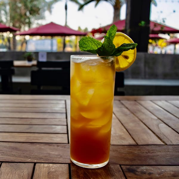 Tall glass of iced tea with lemon and mint on a wooden table at The Shop: Pizza + Cocktails.